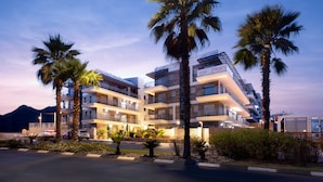 A multi-story hotel with balconies, palm trees, and a mountain in the background. - Light Filled Modern Eilat Getaway (Eilat)