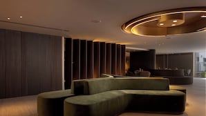 A modern, curved sectional sofa in a spacious, well-lit room with a wooden floor and a unique circular ceiling light fixture. - Light Filled Modern Eilat Getaway (Eilat)