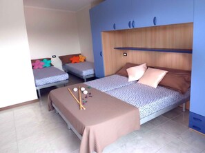 Un dormitorio con dos camas individuales, una cama grande y una mesita con una manta y un juego de mesa.