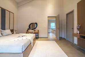 A modern bedroom with a large bed, a desk, and a mirror. There is a view of a balcony through an open door. - Staymaster Casa Nivara (Siolim)
