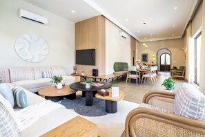 A modern living room with a sofa, coffee table, and dining area. - Staymaster Casa Nivara (Siolim)