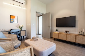 A modern living room with a flat-screen TV, a sofa, a coffee table, and a dining area with chairs. - Staymaster Casa Nivara (Siolim)