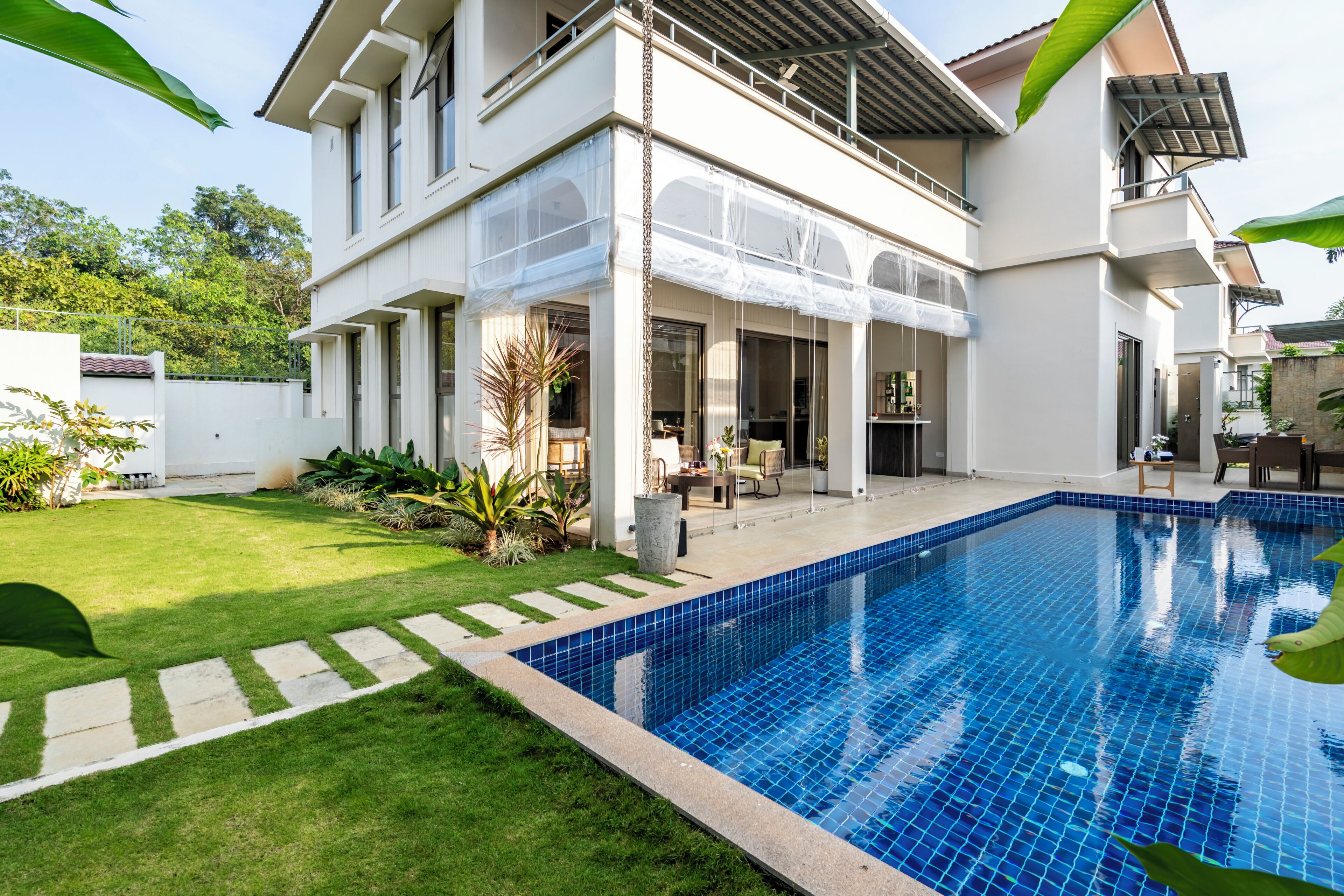 A two-story house with a swimming pool, a covered patio, and a well-maintained lawn.