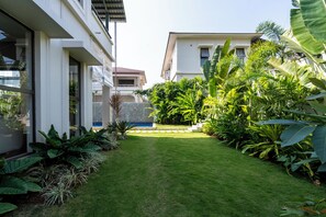 A modern house with a well-maintained lawn and tropical plants. - Staymaster Casa Nivara (Siolim)