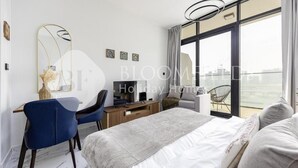 Et moderne hotelværelse med en stor seng, et skrivebord med stol, et fjernsyn og en balkon med en stol.