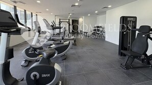 Et fitnessrum med løbebånd, crosstrainere og styrkeudstyr.