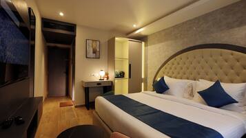 Una habitación de hotel con cama, escritorio, silla, televisor y puerta.