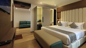 A modern hotel room with a large bed, a sofa, a desk, and a built-in wardrobe. - Grand Plaza Inn by RAK Rooms Kannur (Kannur)