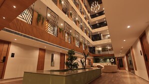 A multi-level hotel lobby with a central island, wooden flooring, and modern decor. - Grand Plaza Inn by RAK Rooms Kannur (Kannur)