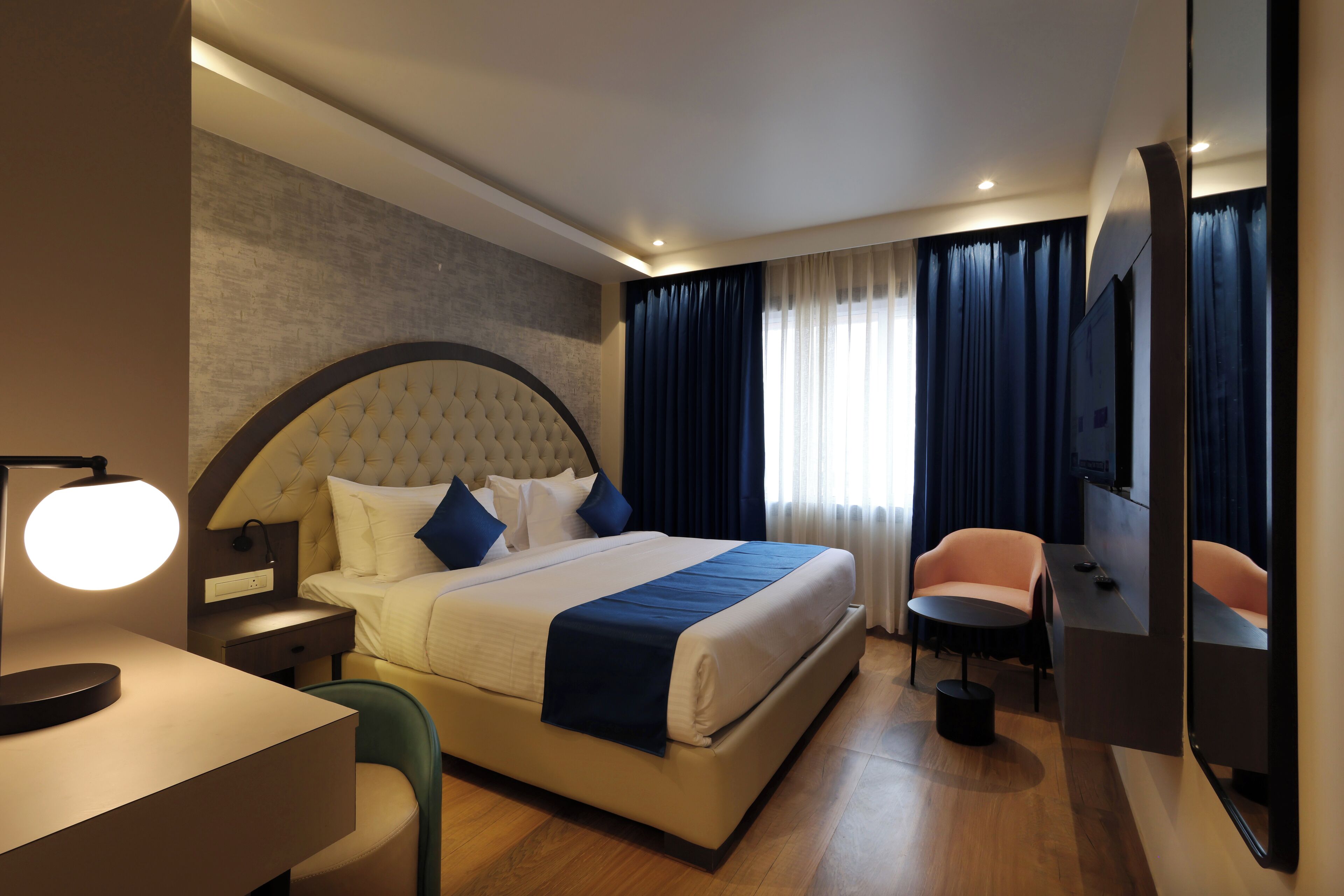 Een moderne hotelkamer met een groot bed, een bureau, een stoel, een televisie en een spiegel.
