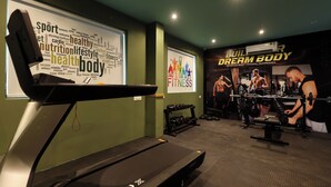 A gym with a treadmill, dumbbells, and a poster advertising advanced body training techniques. - Grand Plaza Inn by RAK Rooms Kannur (Kannur)
