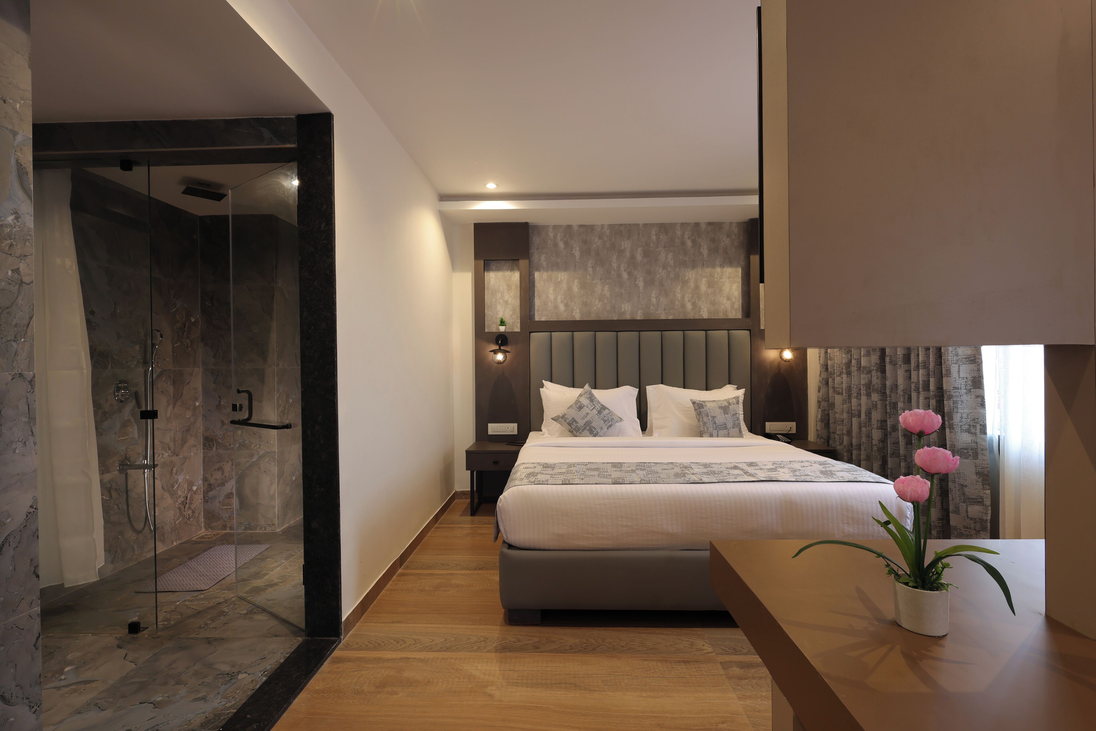 Un dormitorio moderno con una cama grande, una mesita de noche y una planta en maceta. Incluye una zona de ducha.