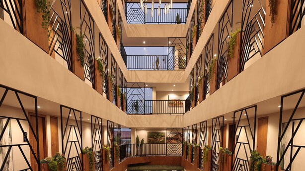 A multi-level atrium with wooden flooring, geometric wall designs, and indoor plants. - Grand Plaza Inn by RAK Rooms Kannur (Kannur)