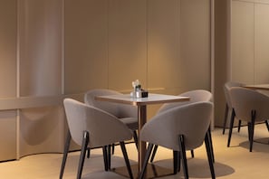 Uma área de jantar moderna com uma mesa redonda e quatro cadeiras, um vaso com flores e um design minimalista.