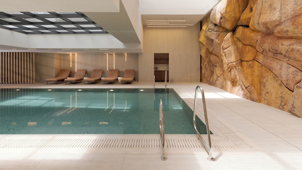 An indoor swimming pool with a rock wall, lounge chairs, and a skylight. - Sunlit Desert View Modern Retreat (Eilat)