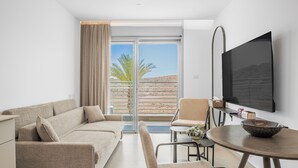 A modern living room with a sofa, a dining table, and a TV. - Sunlit Desert View Modern Retreat (Eilat)