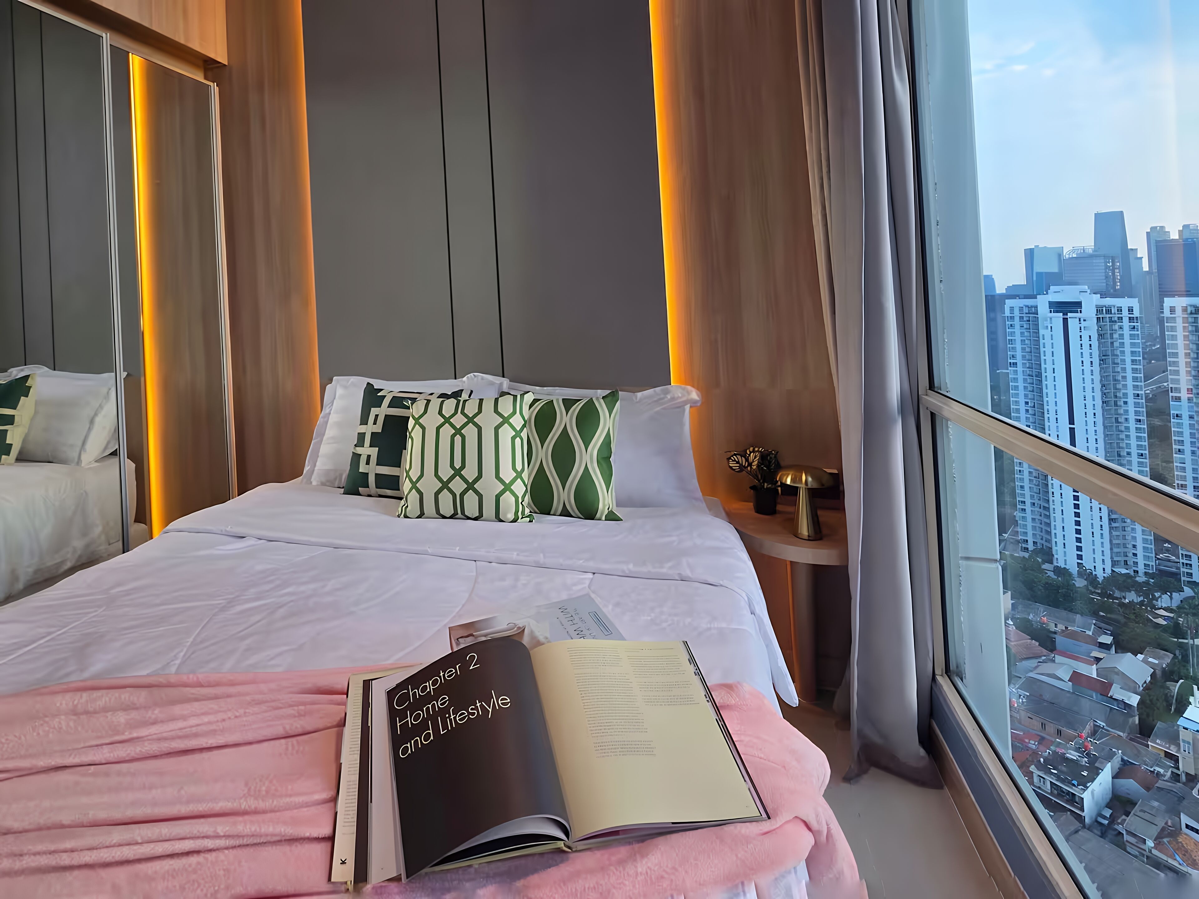 A modern hotel room with a large bed, a bedside table with a lamp, and a view of the cityscape through the window.