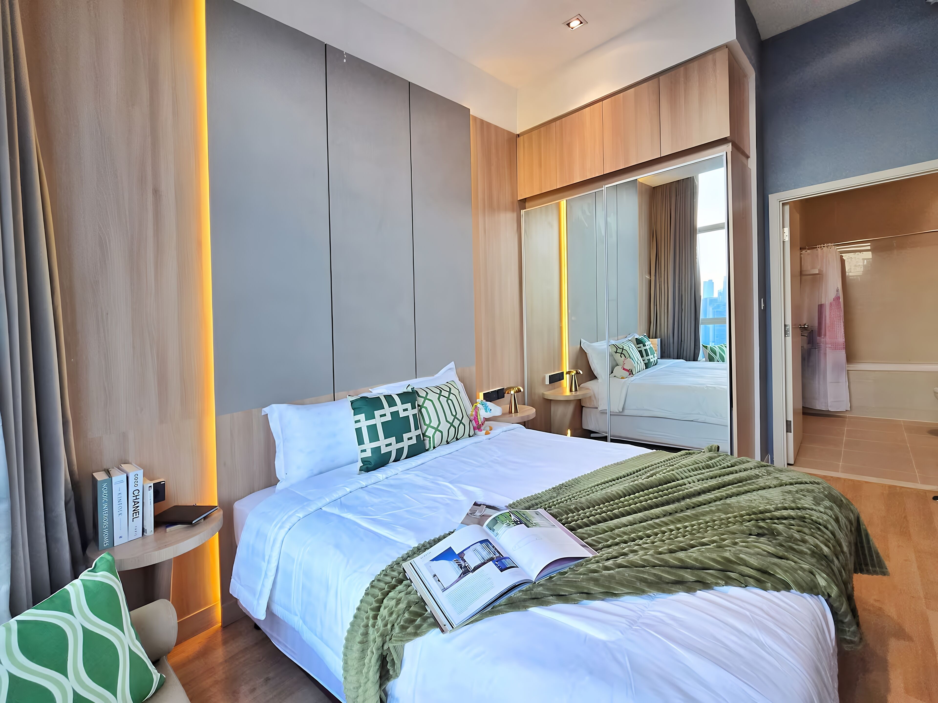 Habitación de hotel moderna con una cama grande, mesitas de noche, un espejo y vistas a la ciudad.