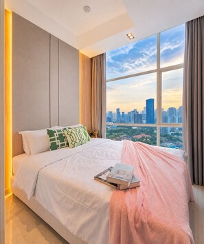 Une chambre moderne avec un grand lit, une vue sur la ville et un livre posé sur le lit.