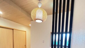 Um corredor com soalho de madeira, luminária pendente e divisória vertical preta.