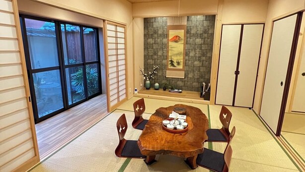Quarto japonês tradicional com tatames, uma mesa de madeira baixa e biombos shoji.