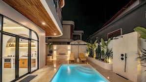 Ein moderner Innenpoolbereich mit klarem Becken, Liegestühlen und hellem Ambiente mit Holzboden.