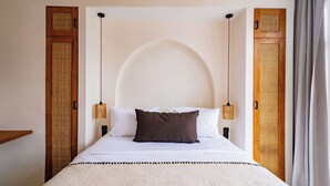 Ein Bett mit großem, halbkreisförmigen Kopfteil, zwei Nachttischlampen und einem gewebten Teppich.