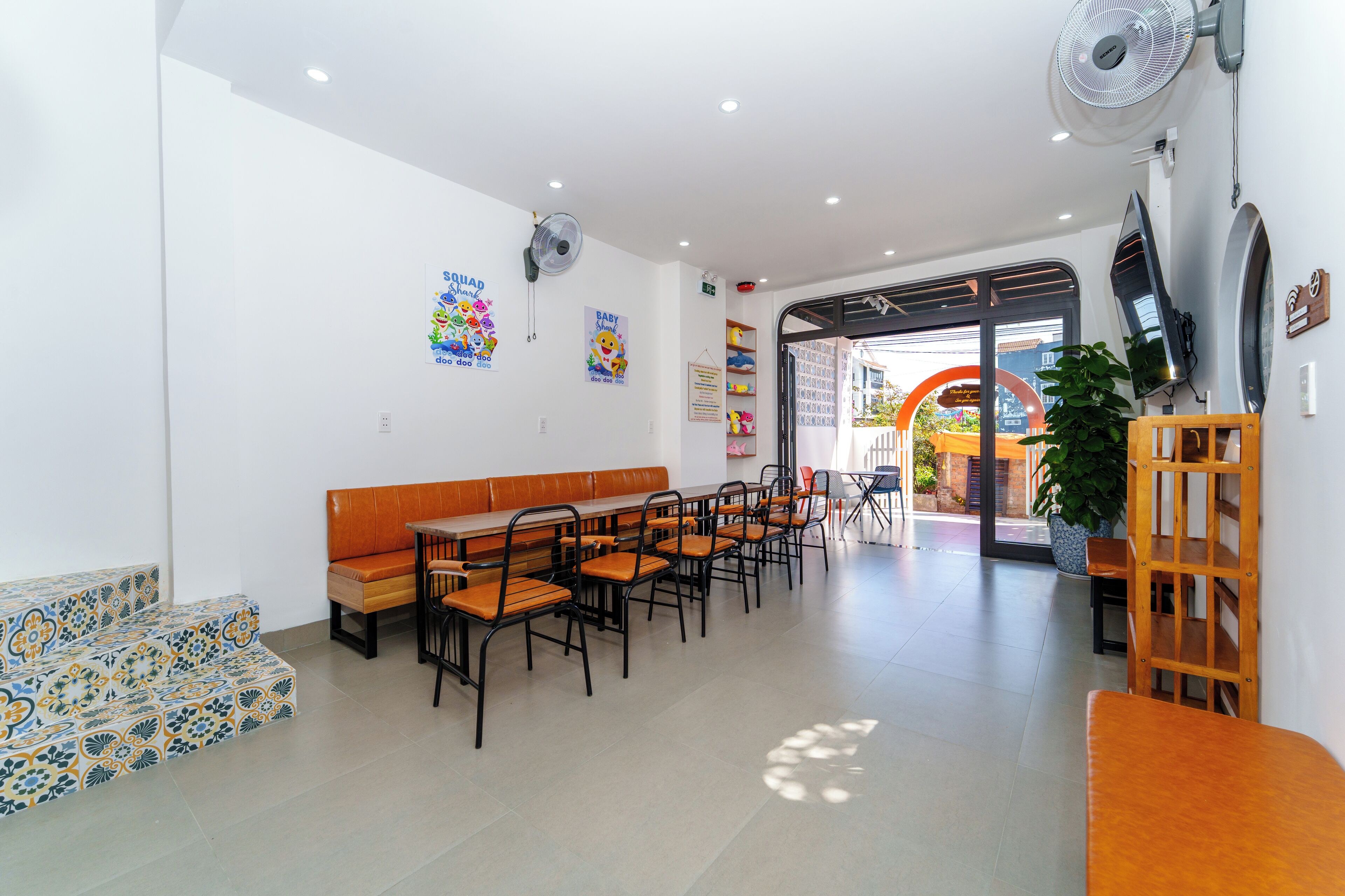 A spacious room with a long table and chairs, a bench, and a potted plant.