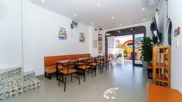 A spacious room with a long table and chairs, a bench, and a potted plant.