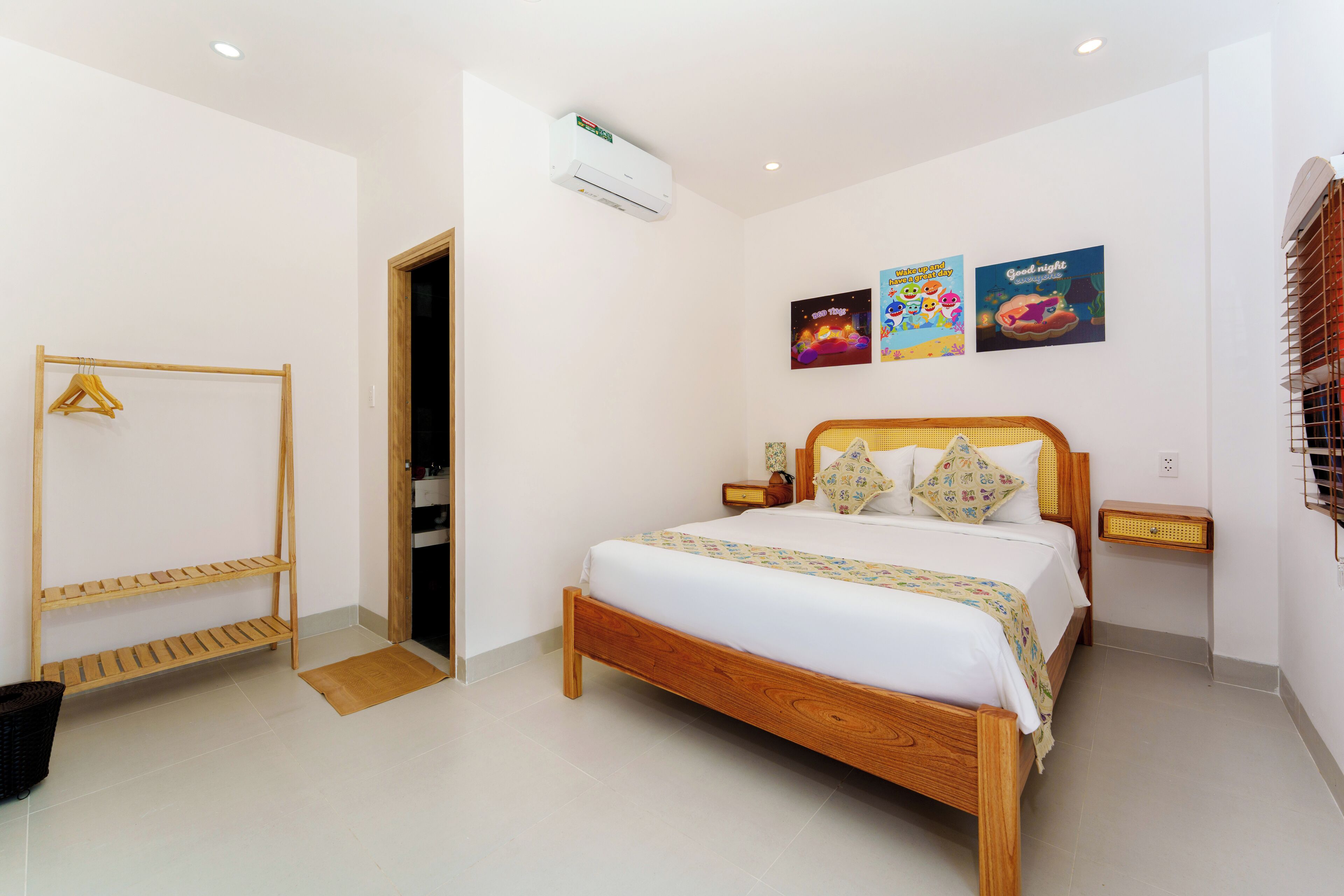 A bedroom with a wooden bed, a wooden shelf, a wall-mounted air conditioner, and a small bedside table with a radio.