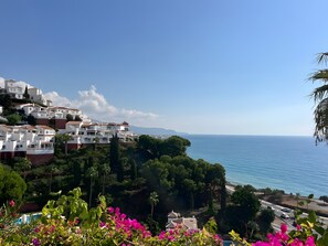 Un pueblo costero con edificios blancos, un cielo azul despejado y vista al mar.