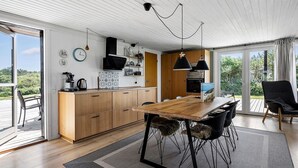 Une cuisine moderne avec des meubles en bois, une table à manger et une grande fenêtre.