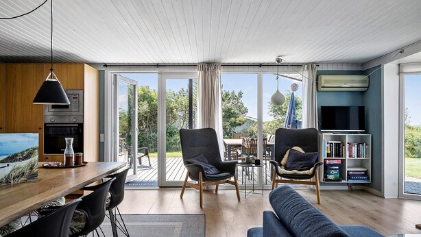 Un salon moderne avec une table à manger en bois, deux fauteuils, un canapé et un téléviseur.