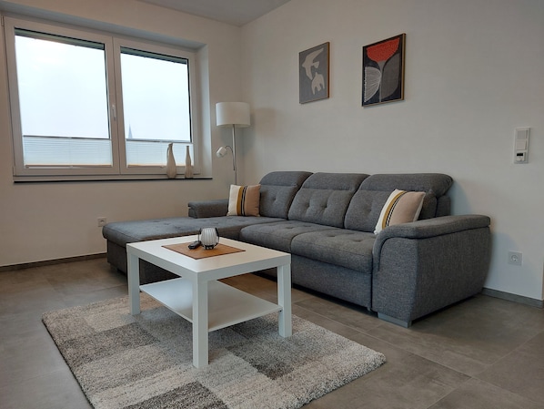Una sala de estar moderna con un sofá gris, una mesa de centro blanca y un tapete estampado.
