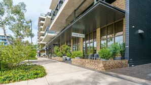 A modern building with a 'WINE SHOP' sign, outdoor seating, and potted plants. - Premium Apartment with Scenic Views near City (Campbell)