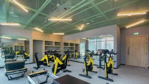 Une salle de sport équipée de matériel d’exercice, de miroirs et dotée d’une grande fenêtre.