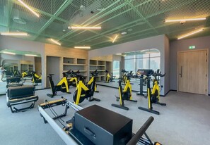 Ein Fitnessstudio mit Trainingsgeräten, Spiegeln und einem großen Fenster.