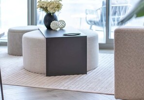 A modern room with a dark square table, a vase with flowers, and a round ottoman. - Canal Views Apt W Balcony Pool & Gym Access (Dubai)