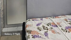 Ein Schlafzimmer mit einem Galaxy Z Flip5 Bett, einem Kleiderschrank und einem floralen Gemälde an der Wand.