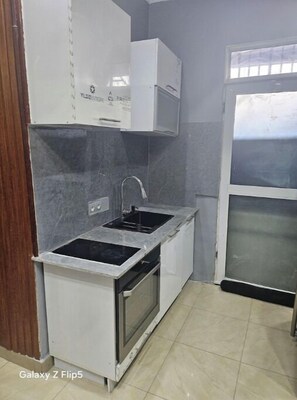 A compact kitchen with a built-in oven, a sink, and a microwave.