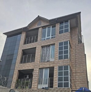 A multi-story building with a modern architectural design, featuring balconies and large windows.