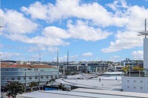Eine Dachterrasse mit freiem Blick auf die Stadtlandschaft, darunter moderne Gebäude und ein Yachthafen.
