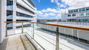 Un edificio moderno con varios pisos, ventanas grandes y barandilla de balcón de vidrio.