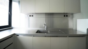 Una cocina moderna con electrodomésticos de acero inoxidable, un ventanal y un lavamanos empotrado.