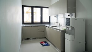 Cocina moderna con armarios blancos, un refrigerador de acero inoxidable y una ventana con vista a una construcción.