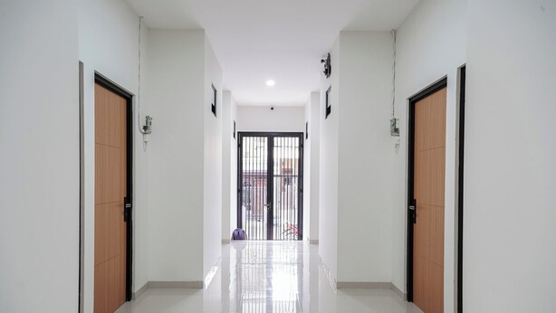 Un pasillo con dos puertas a cada lado, que conduce a un par de puertas al final.