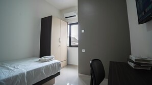 Una habitación pequeña y moderna con cama, armario, escritorio y silla.