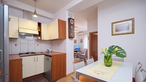 Una cocina moderna con armarios de madera, lavavajillas integrado y un comedor con mesa y sillas.