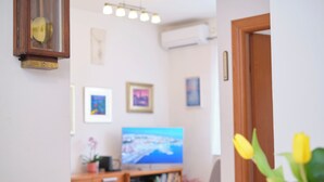 Una sala de estar con televisor, estantería y puerta.