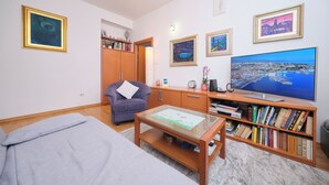 Una sala de estar con un sofá, una mesa de centro, una estantería, un televisor y obras de arte enmarcadas en las paredes.